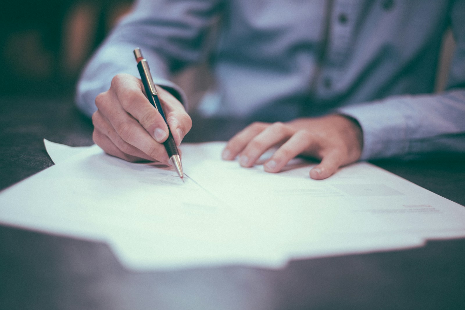 man writing on paper explaining how increased claims impact insurance rates